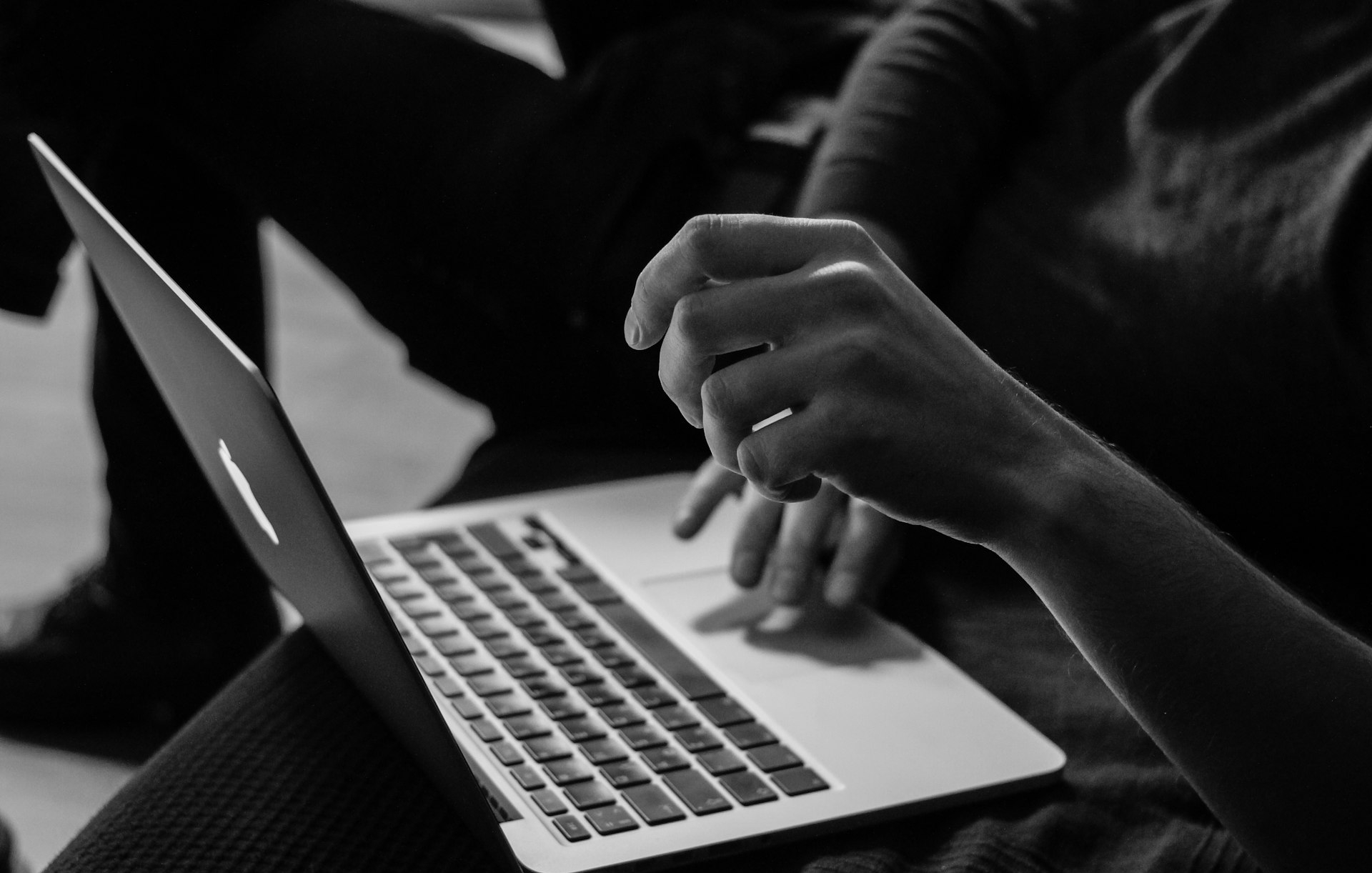 grayscale photo of person using MacBook